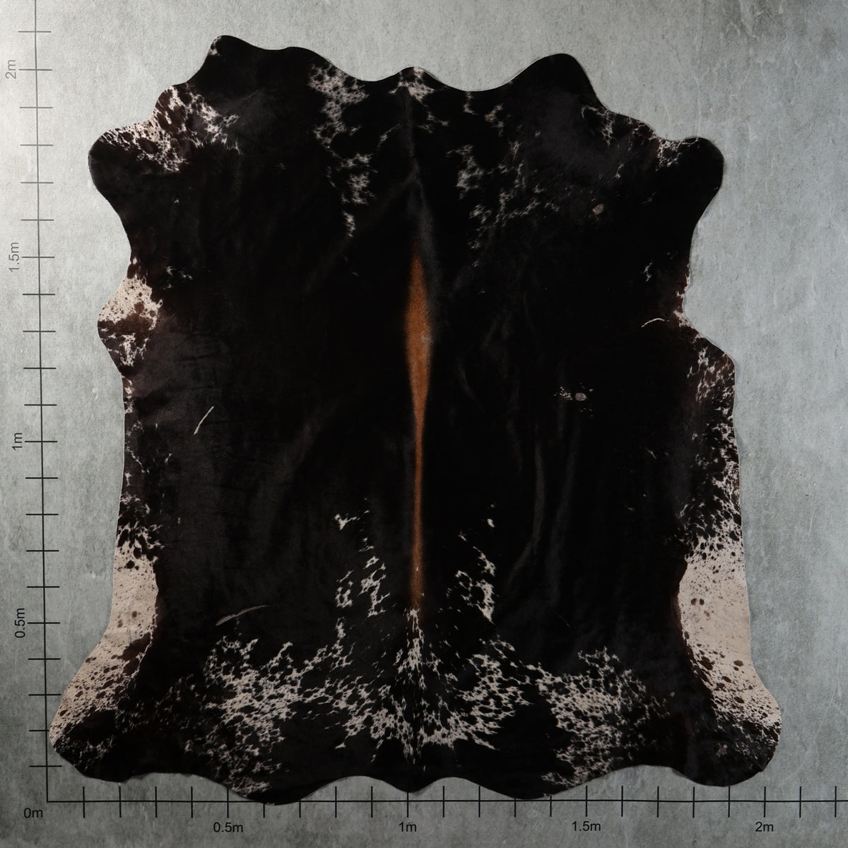 Genuine South African black Nguni cowhide with white speckled edges, mottled markings and a narrow reddish-brown central streak – BGS2749.