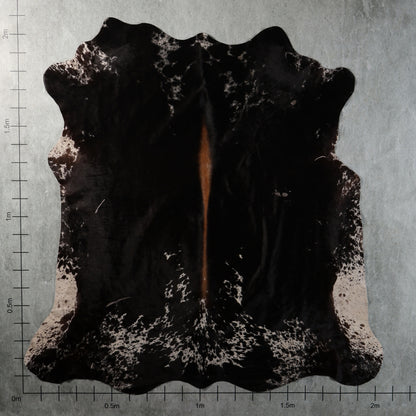 Genuine South African black Nguni cowhide with white speckled edges, mottled markings and a narrow reddish-brown central streak – BGS2749.