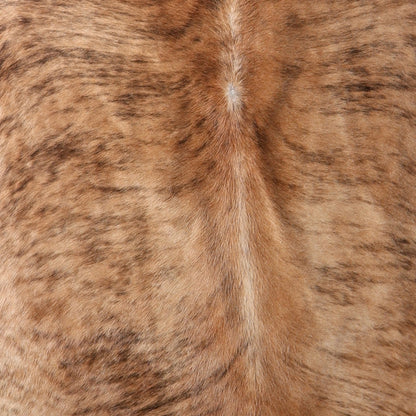 A close-up texture shot of a brown and tan brindle Nguni cowhide showing a central seam with darker brown streaks.