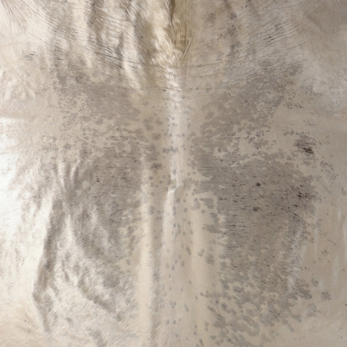 A close-up of a Nguni cowhide rug showing a natural mottled pattern in cream, beige, and gray tones