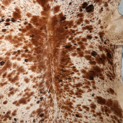 Close up of a brown and cream cowhide rug with a natural spotted pattern.